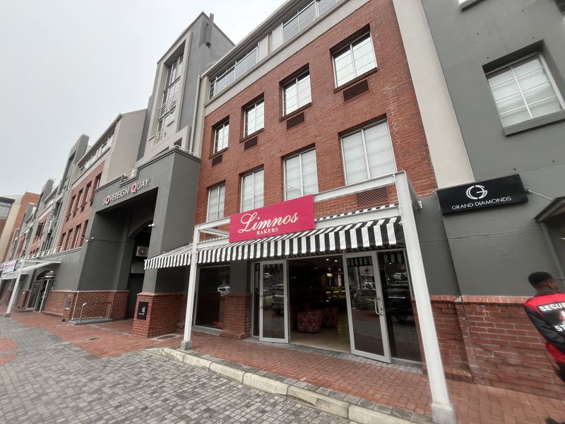 Front exterior view of a commercial building featuring a brick facade, glass storefront entrance, and striped awning at street level.