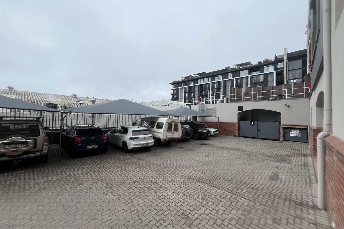 A paved parking area featuring multiple shade cloth carports and secure gated access, situated at the rear of the business premises.