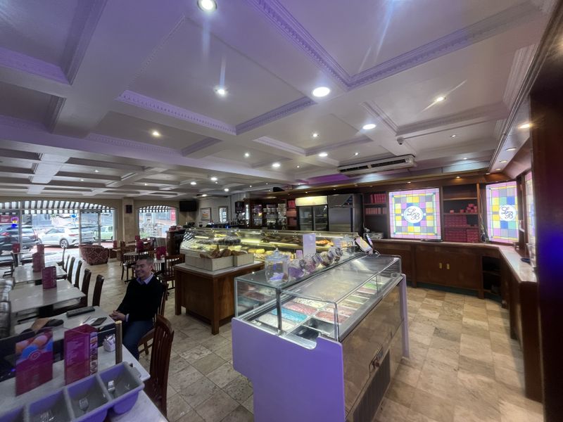 Spacious commercial interior featuring a coffered ceiling, recessed lighting, stone tile flooring, and built-in display cabinetry with integrated glass counters.