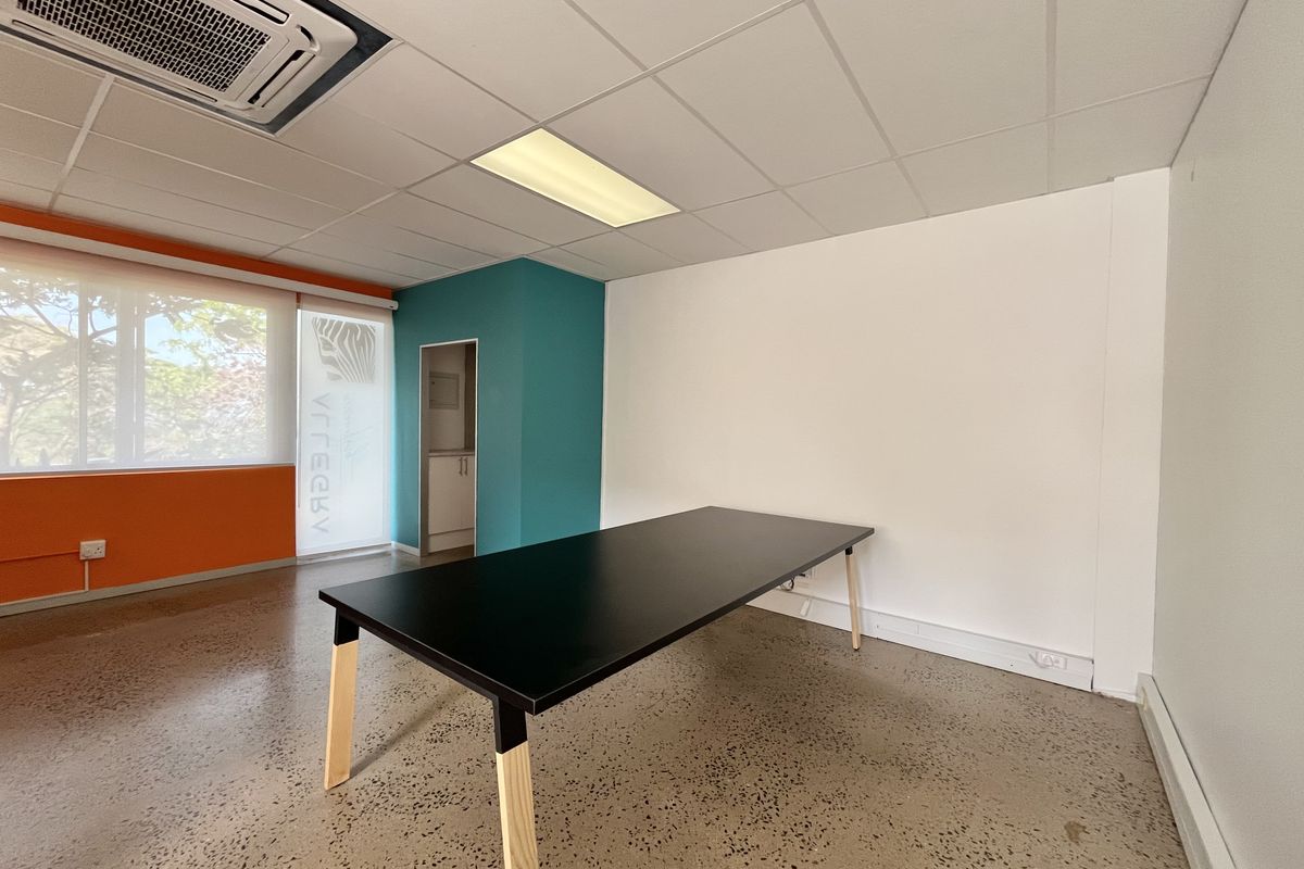 A bright, modern office space featuring polished concrete floors, a suspended ceiling with integrated air conditioning, and vibrant accent walls.