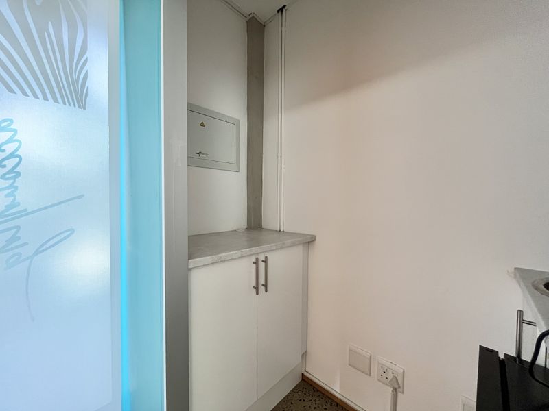 A functional utility area featuring built-in cabinetry with a laminate countertop and an integrated electrical distribution board.