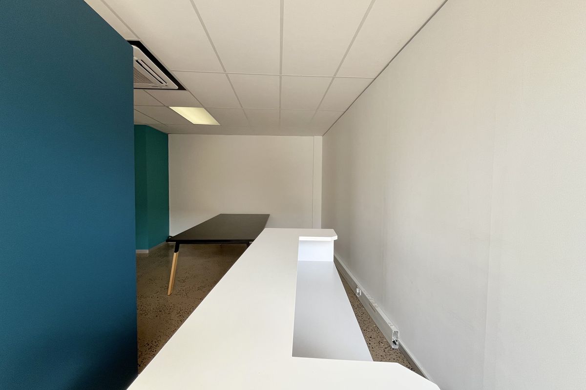 A modern office space featuring a built-in reception desk, polished concrete floors, and a clean, professional aesthetic with recessed lighting.