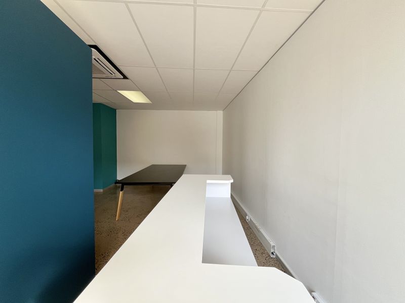 A modern office space featuring a built-in reception desk, polished concrete floors, and a clean, professional aesthetic with recessed lighting.