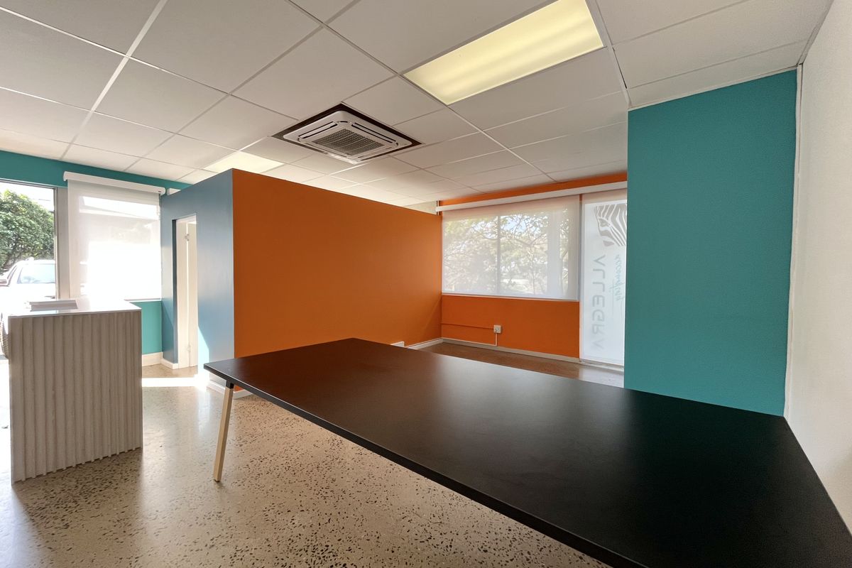 Modern office space featuring vibrant accent walls, terrazzo flooring, suspended ceiling with recessed lighting, and integrated cassette air conditioning.