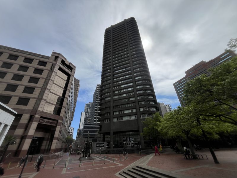 A wide-angle view of a prominent high-rise office building situated in a paved urban plaza setting.