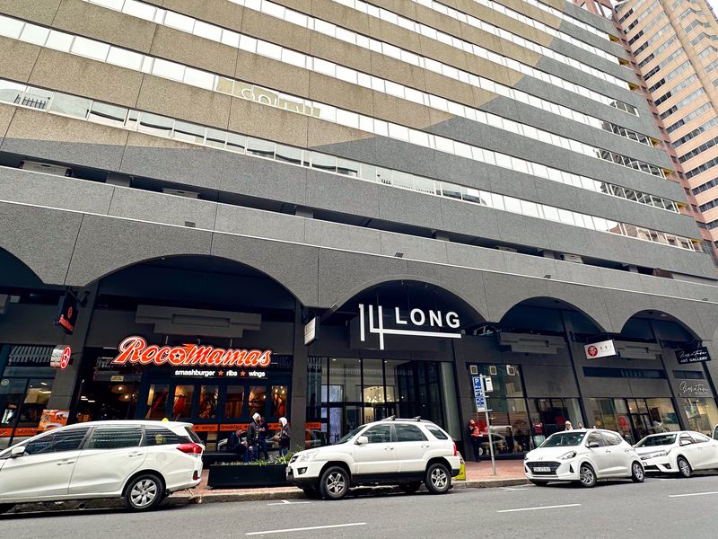 Street-level view of the 14 Long commercial building facade, featuring modern arched architectural detailing and multiple ground-floor retail storefronts.