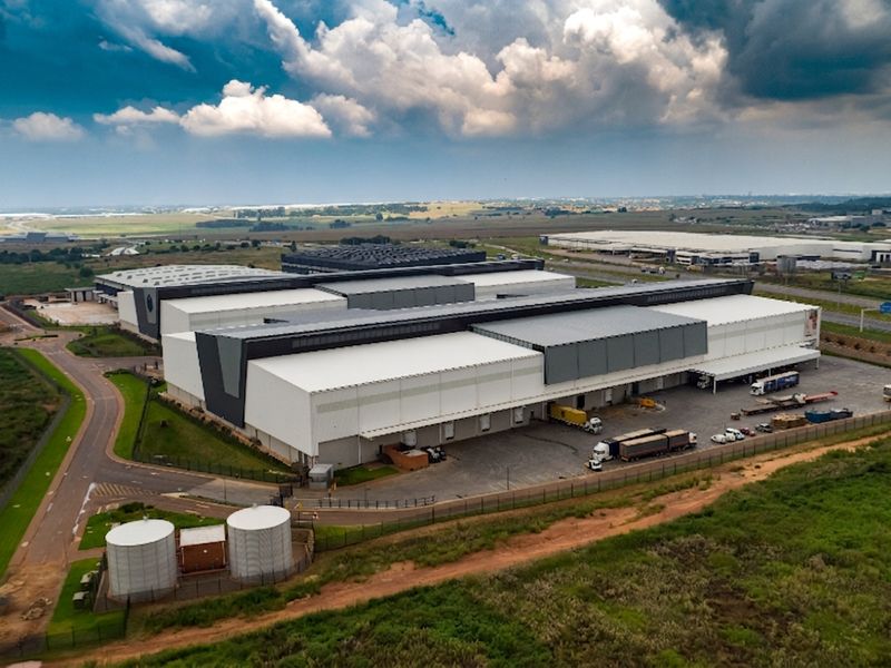 Aerial view of a large industrial warehouse complex featuring multiple loading docks, extensive yard space, and on-site water storage tanks.