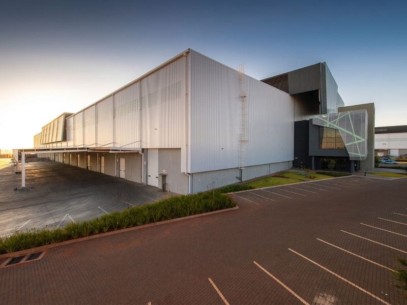 Modern industrial warehouse facility featuring extensive loading bays, paved parking, and high-quality metal cladding exterior.