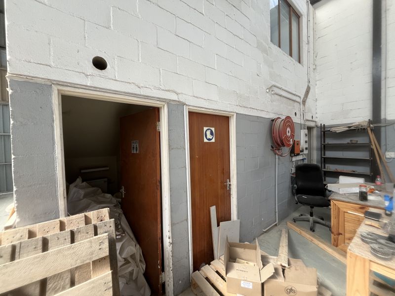 Industrial utility space featuring exposed concrete block walls, fire safety equipment, and access to internal toilet facilities.