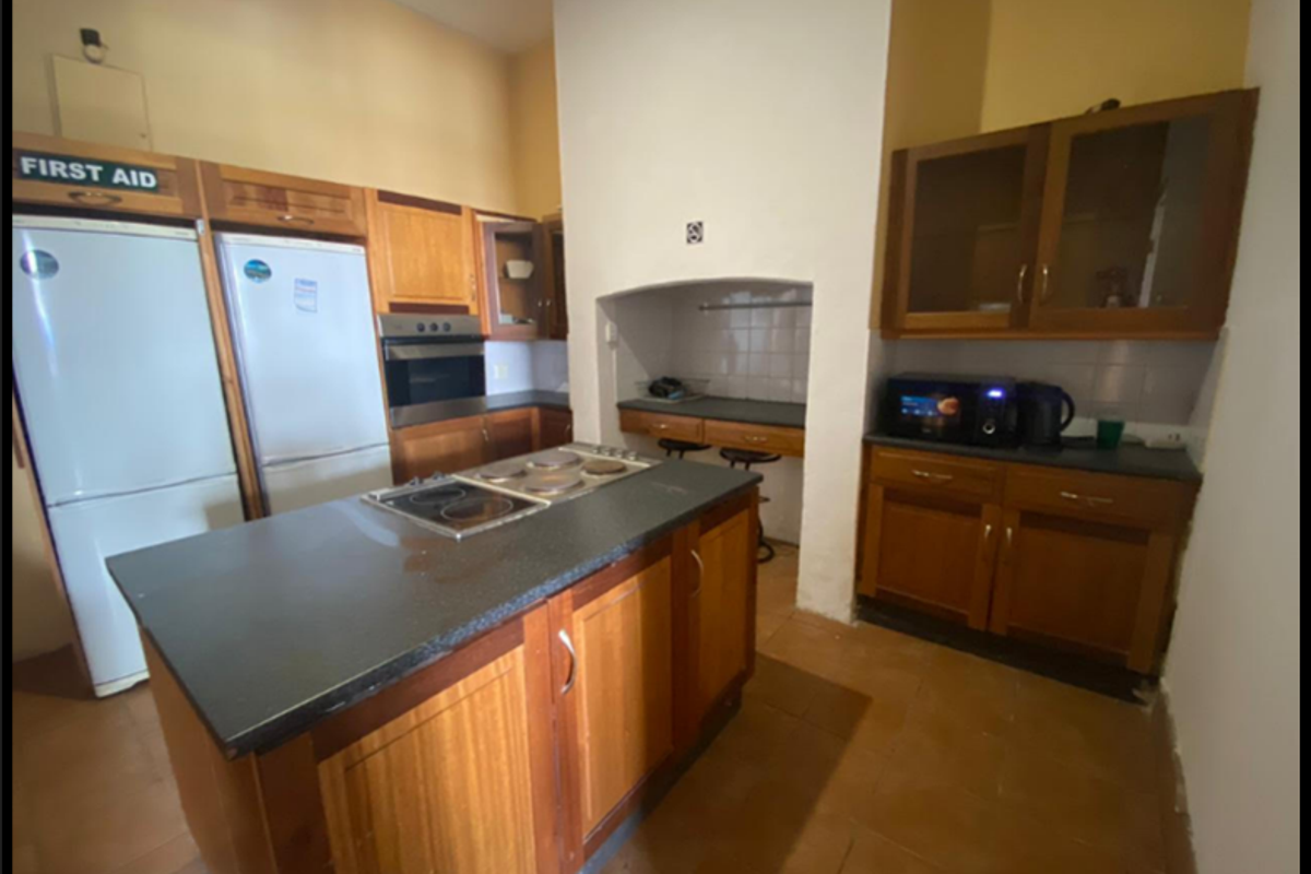 A functional kitchen featuring wooden cabinetry, a central island with a built-in hob, stone countertops, and a dedicated breakfast nook area.