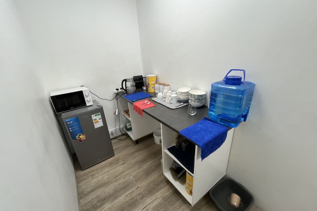 A compact office kitchenette featuring laminate flooring, built-in cabinetry, and a functional countertop area for basic food and beverage preparation.
