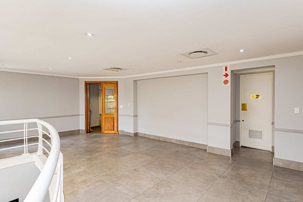A spacious, well-maintained office landing area featuring neutral tiled flooring, recessed lighting, and clean wall finishes, suitable for a professional workspace.