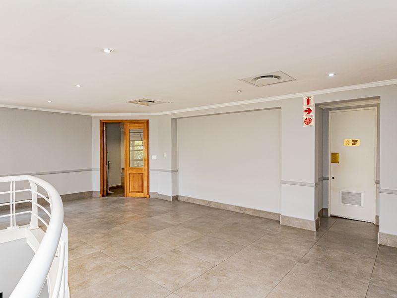 A spacious, well-maintained office landing area featuring neutral tiled flooring, recessed lighting, and clean wall finishes, suitable for a professional workspace.