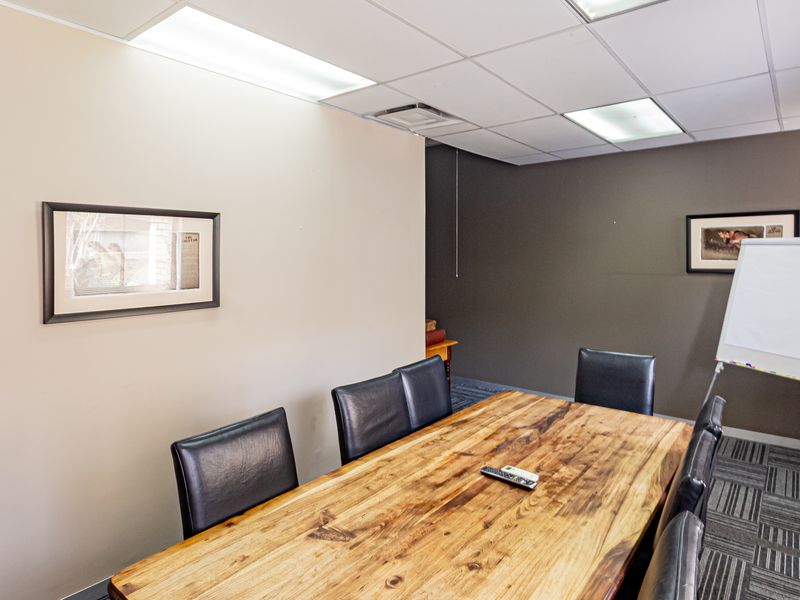 A functional office meeting room featuring a suspended ceiling with recessed lighting and durable carpet tile flooring.