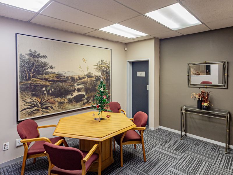 A professional office space featuring a drop ceiling with recessed lighting, carpet tile flooring, and a neutral color palette.