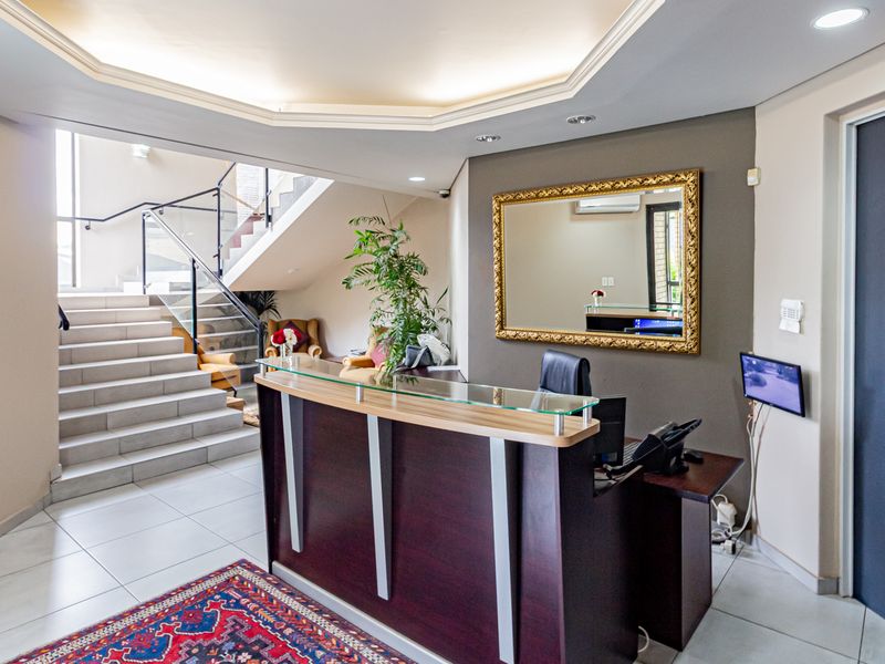 Professional office reception area featuring a built-in reception desk, tiled flooring, and a staircase with a modern glass balustrade.