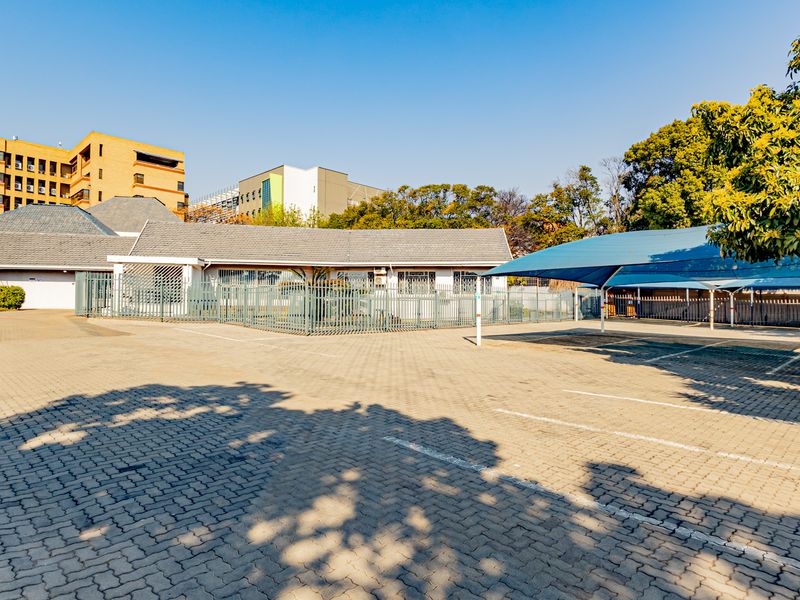 Commercial property exterior featuring a large paved parking area with shade cloth carports and secure perimeter fencing.