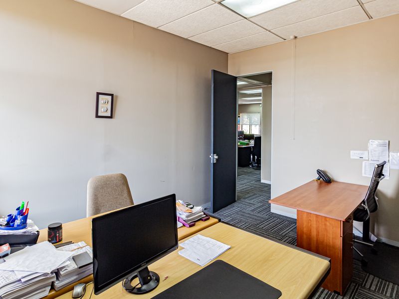 A functional office space featuring carpeted flooring, a suspended ceiling, and neutral wall tones, providing a practical environment for professional work.