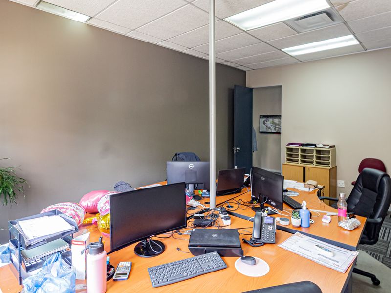 A functional office space featuring carpet tiles, a suspended ceiling with recessed lighting, and built-in storage cabinetry.