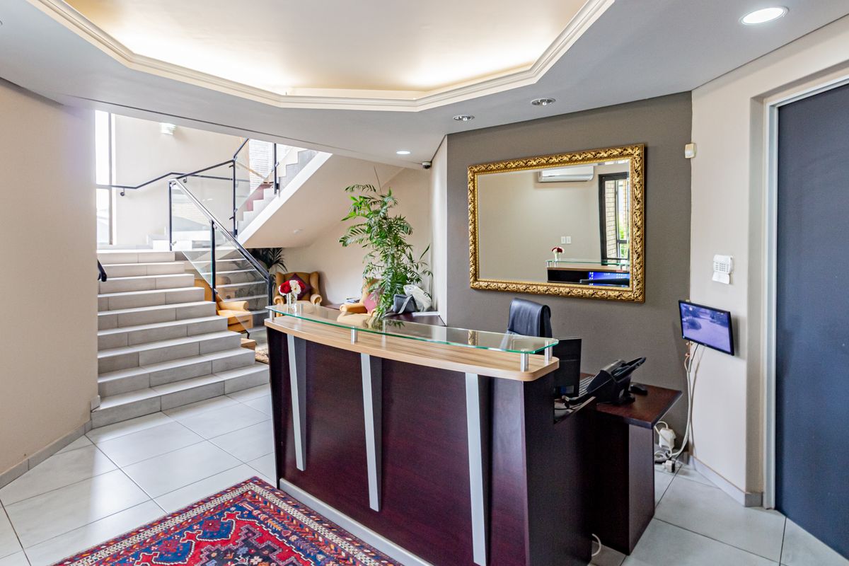 Professional office reception area featuring a built-in reception desk, tiled flooring, and a staircase with a modern glass balustrade.