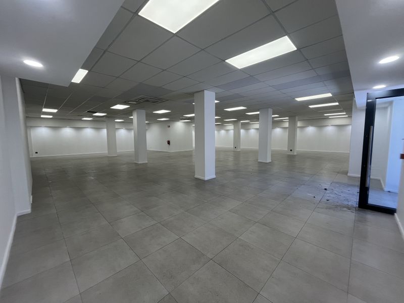 Spacious open-plan retail area featuring neutral tiled flooring, structural columns, and a modern suspended ceiling with recessed lighting.