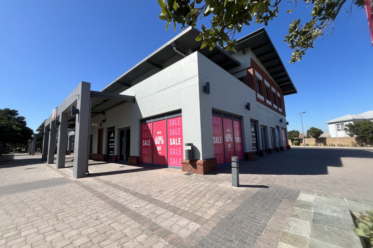 Modern retail storefront featuring a paved entrance area, large display windows, and contemporary architectural design with brick and rendered facade elements.