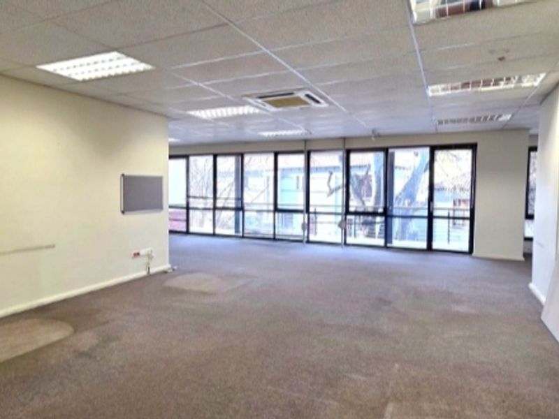 A spacious, open-plan office area featuring large windows, suspended ceilings with recessed lighting, and integrated air conditioning, offering a versatile workspace.