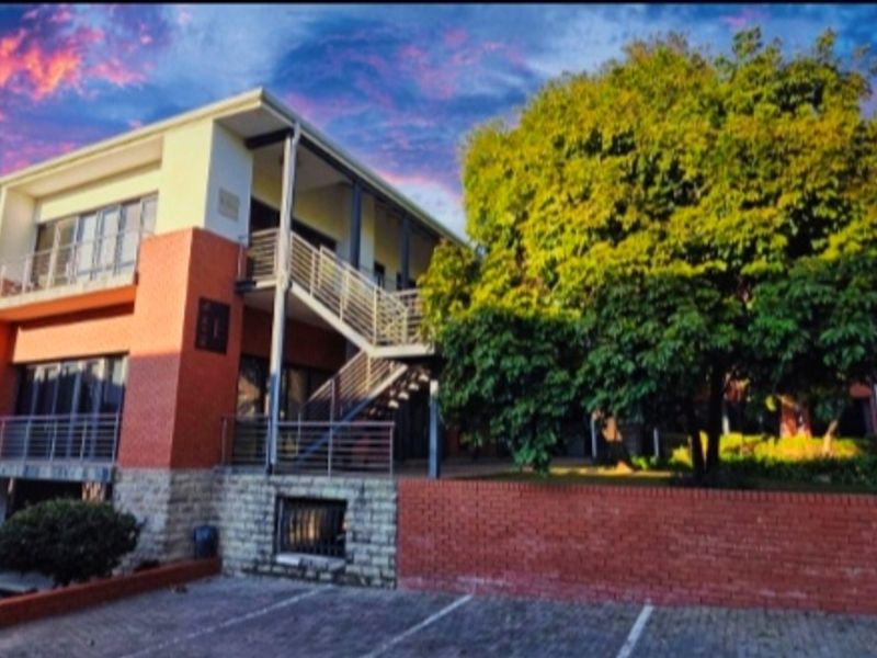 A multi-story office building featuring a combination of brick and stone facade, external staircases, and dedicated paved parking.