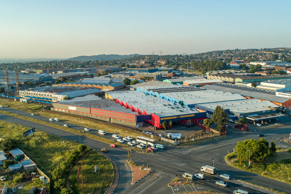 Aerial view of the Supreme Industrial Park complex, showcasing the extensive warehouse facilities, metal roofing, and surrounding road infrastructure in an industrial zone.