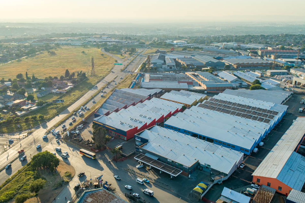 Aerial view of an industrial warehouse complex featuring multiple large-scale buildings with metal roofing, situated near major access roads and surrounding commercial infrastructure.