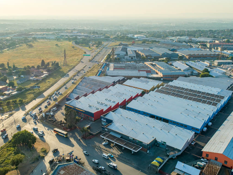 Aerial view of an industrial warehouse complex featuring multiple large-scale buildings with metal roofing, situated near major access roads and surrounding commercial infrastructure.