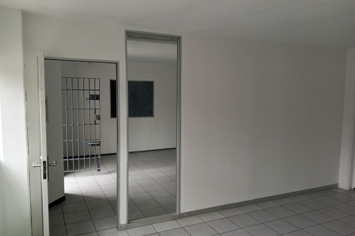 An empty utility space featuring tiled flooring and a secure metal gate, suitable for storage or specialized industrial use.