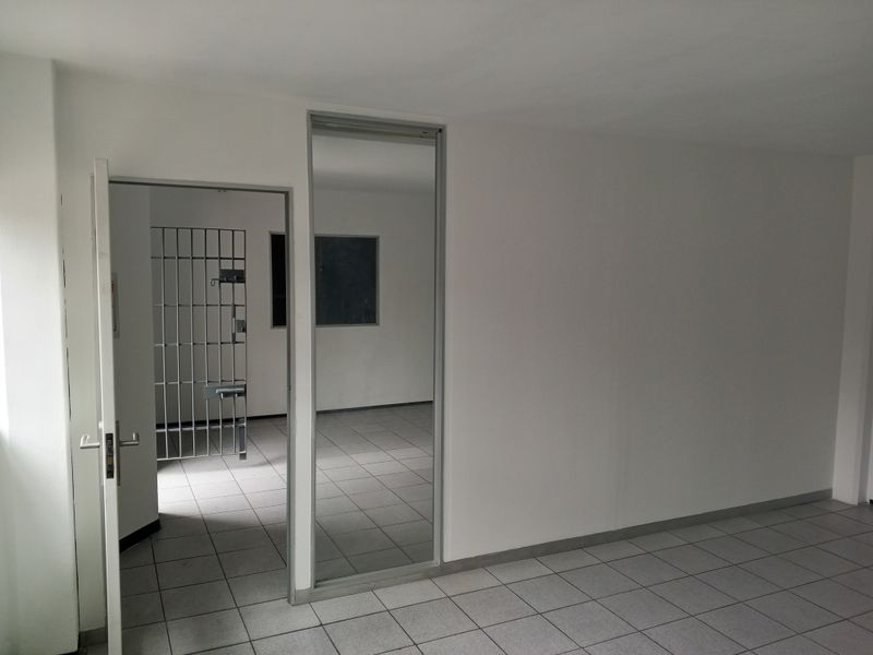 An empty utility space featuring tiled flooring and a secure metal gate, suitable for storage or specialized industrial use.