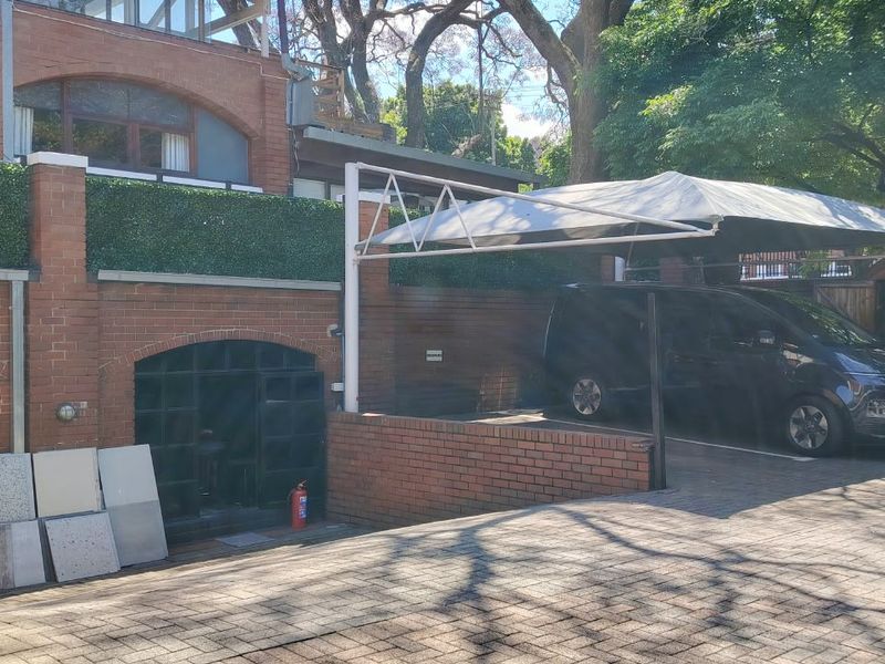 Front exterior view of the office property featuring a brick facade, arched windows, and a covered carport area with paved driveway.