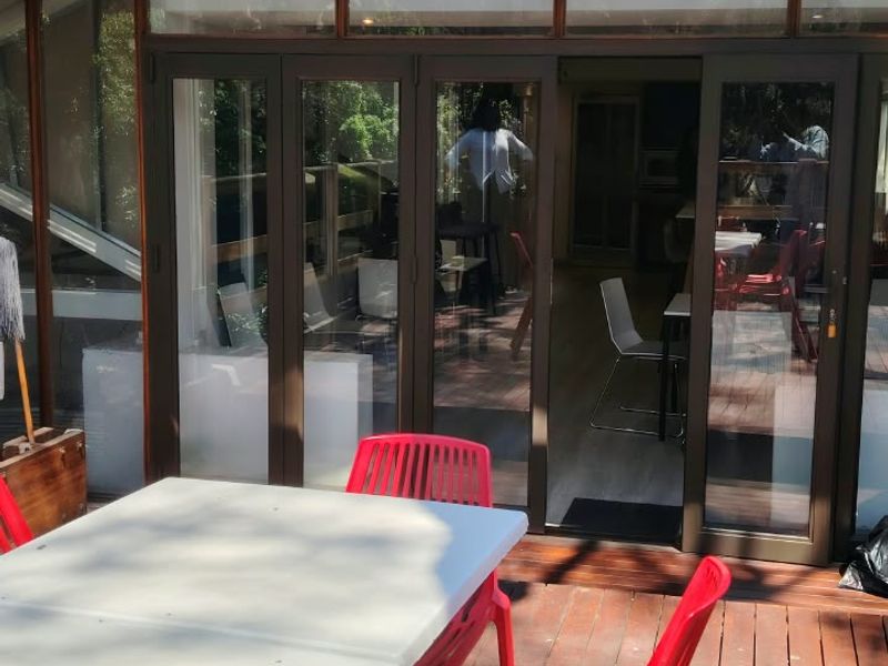 A spacious outdoor timber deck featuring large glass folding doors and exposed timber roof trusses, providing a seamless transition to the interior office space.