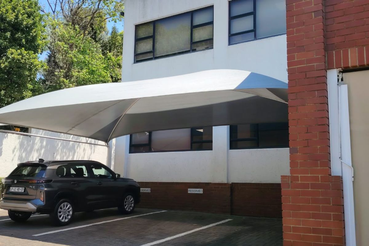 Exterior view of the office building featuring a covered shade port parking area and paved surface.