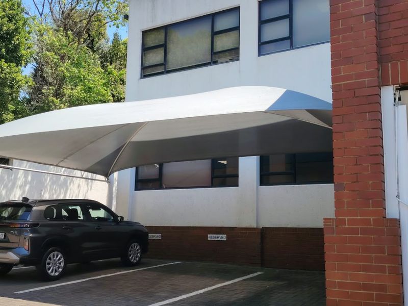 Exterior view of the office building featuring a covered shade port parking area and paved surface.