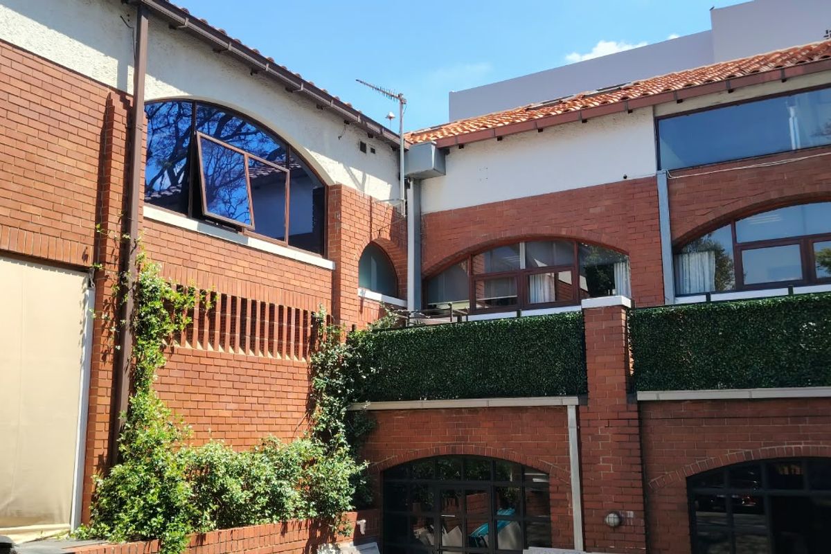 A view of the rear exterior of the office building, featuring exposed brickwork, arched windows, and a terracotta tiled roof.