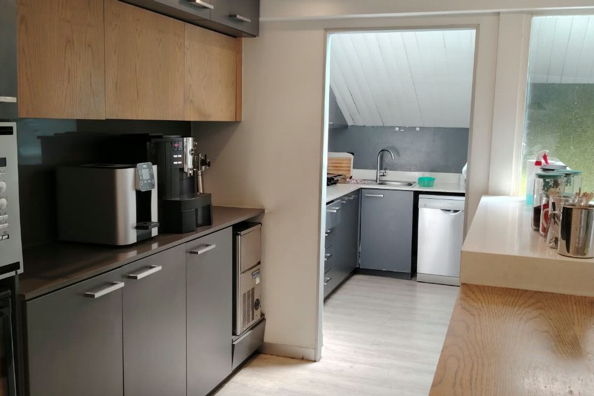 Modern kitchen featuring sleek grey cabinetry, integrated appliances, and a functional scullery area with additional sink and dishwasher.