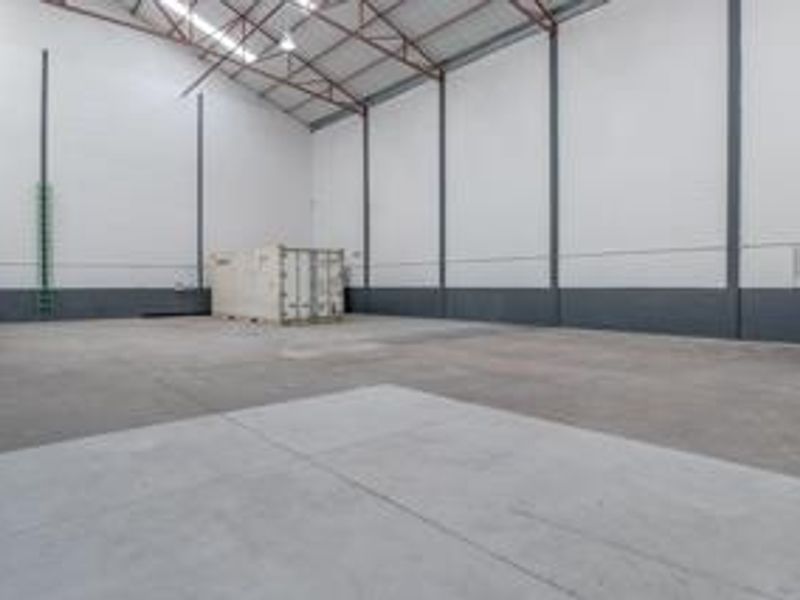 Spacious industrial warehouse unit featuring high-clearance ceilings, exposed steel trusses, and durable concrete flooring, suitable for storage or light manufacturing operations.