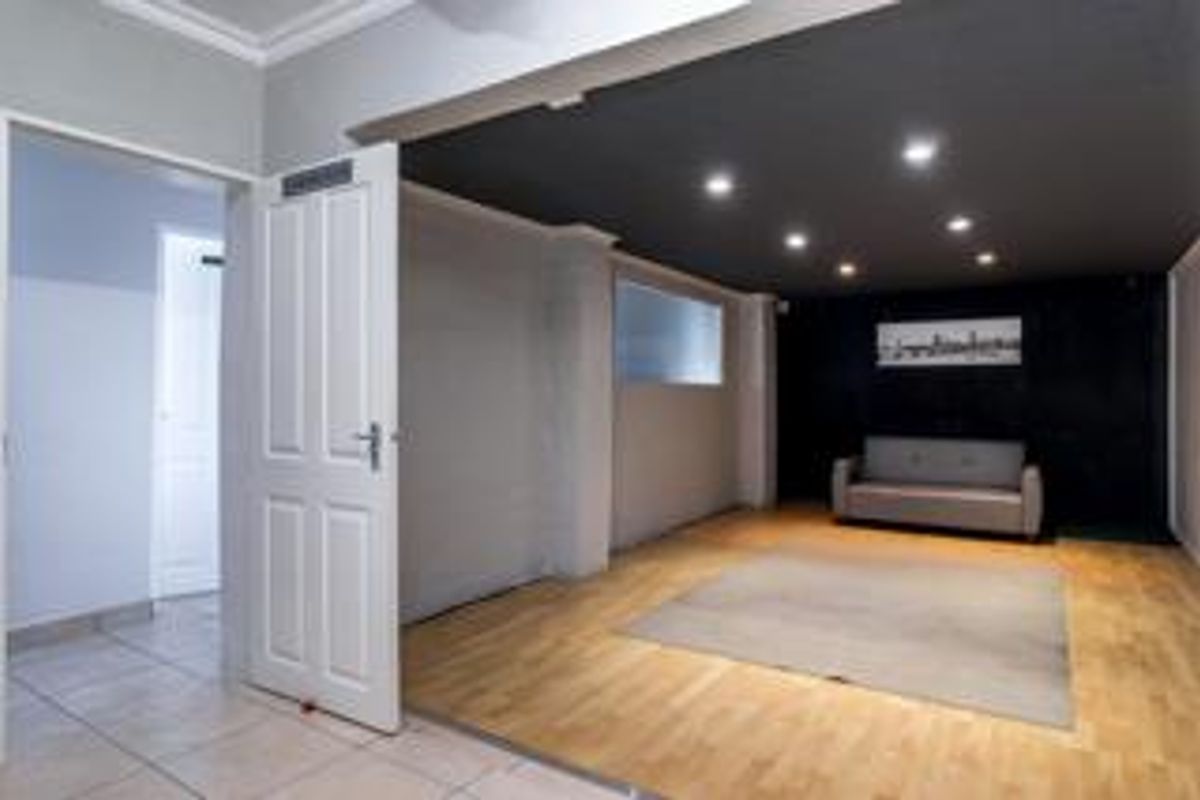 A spacious living area featuring a combination of hardwood and tiled flooring, recessed downlighting, and a modern dark-painted ceiling accent.