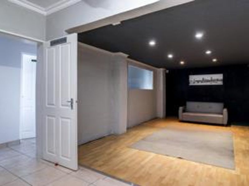 A spacious living area featuring a combination of hardwood and tiled flooring, recessed downlighting, and a modern dark-painted ceiling accent.