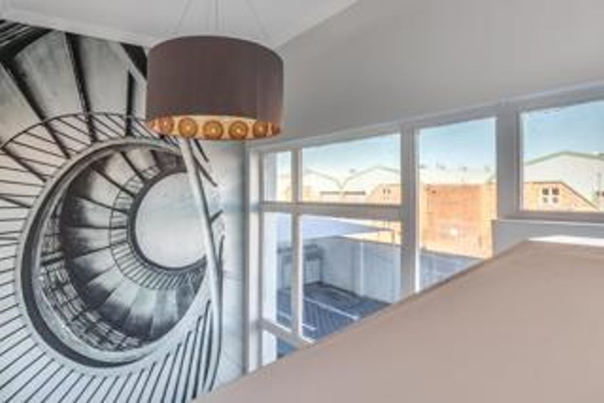 A bright, open office space featuring large windows with exterior views and a modern pendant light fixture.