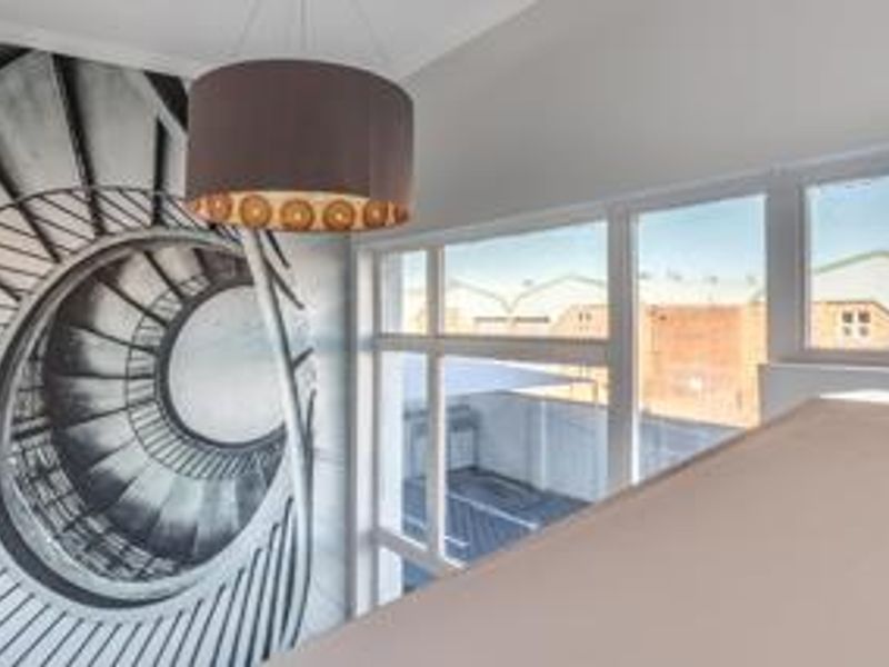 A bright, open office space featuring large windows with exterior views and a modern pendant light fixture.