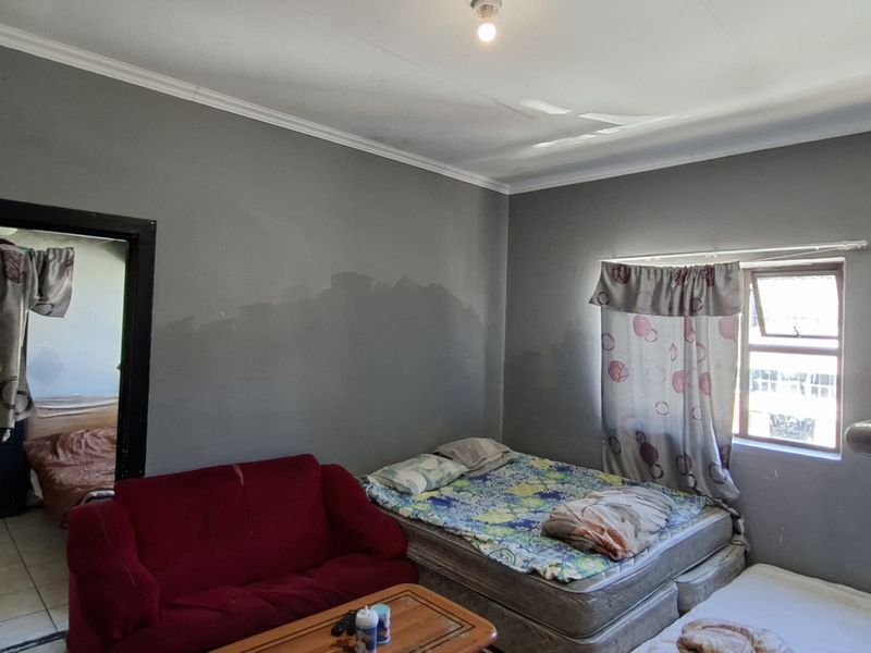 A bedroom featuring grey walls with visible paint discoloration, a window, and coving. The space requires cosmetic updates to improve its overall condition.
