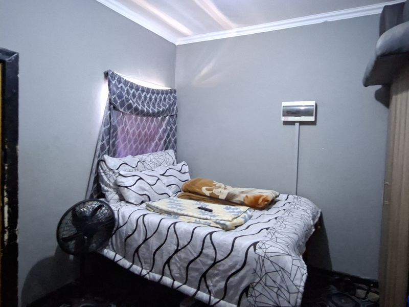 A compact bedroom featuring a built-in wardrobe and an exposed electrical distribution board on the wall.