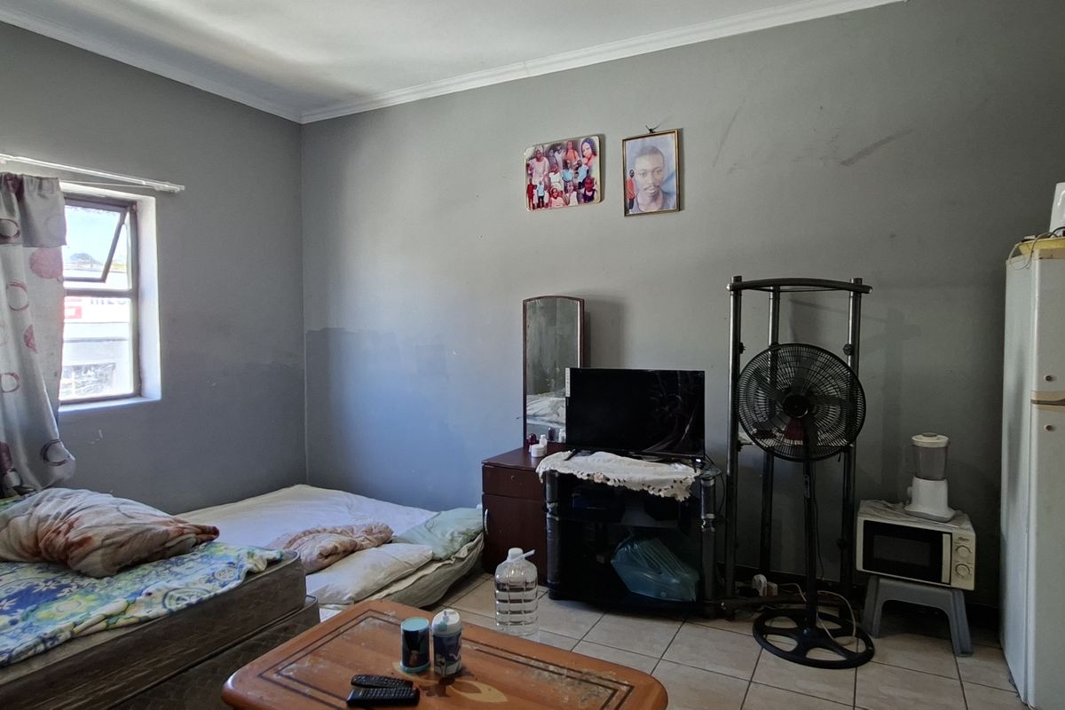 A bedroom featuring tiled flooring and grey painted walls, requiring cosmetic updates to improve the overall finish and aesthetic appeal.