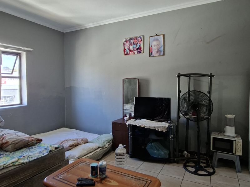 A bedroom featuring tiled flooring and grey painted walls, requiring cosmetic updates to improve the overall finish and aesthetic appeal.