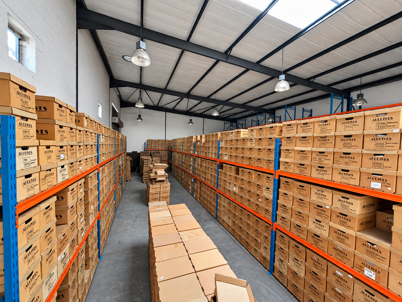 Spacious industrial storage facility featuring high ceilings with exposed steel trusses, skylights, and extensive heavy-duty steel racking systems for organized archival storage.