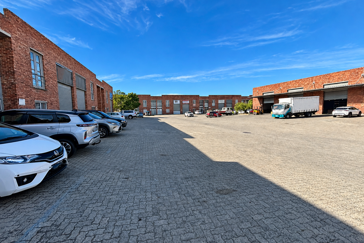 Spacious industrial complex featuring multiple warehouse units with roller shutter doors and a large paved yard area for parking and logistics.